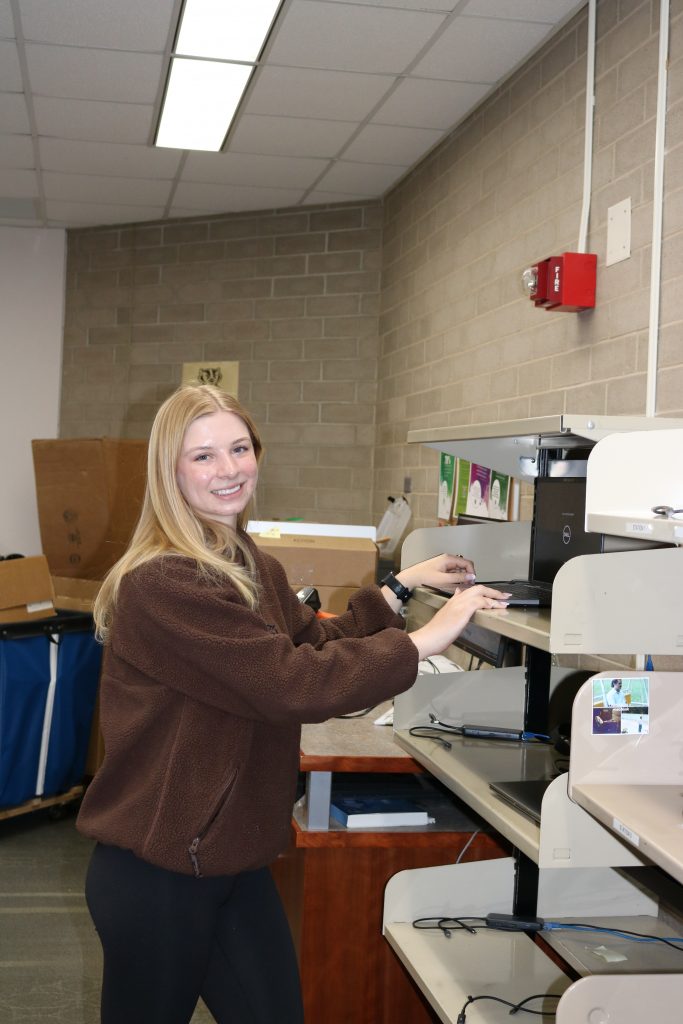A person examines a computer in a stockroom