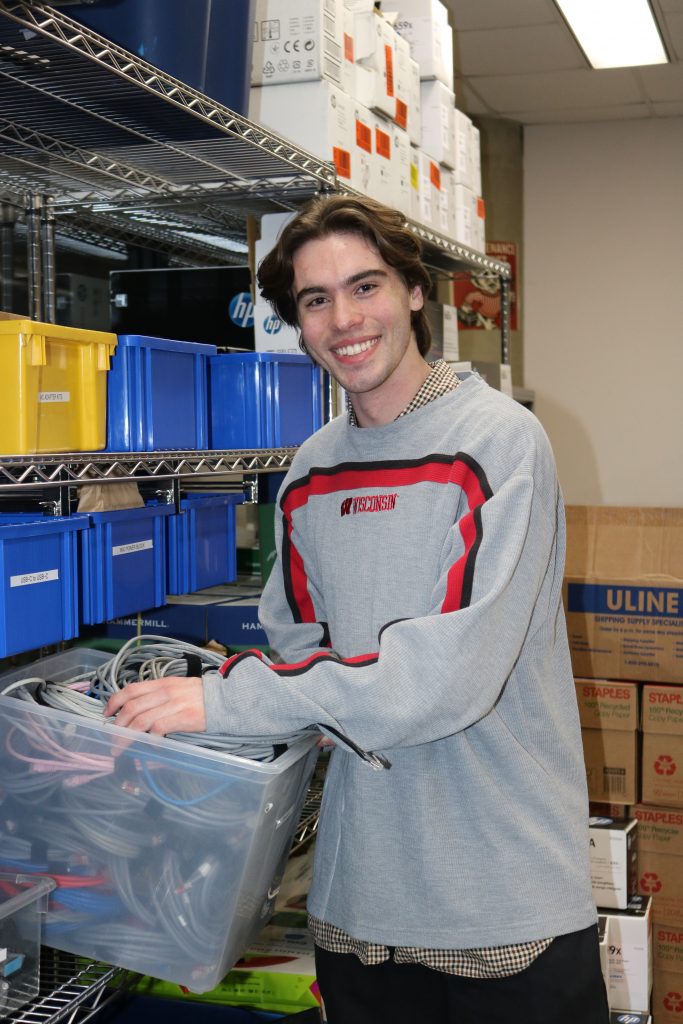 A person examines equipment and wires in a stockroom